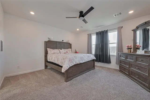 a bedroom with a bed a dresser and potted plant