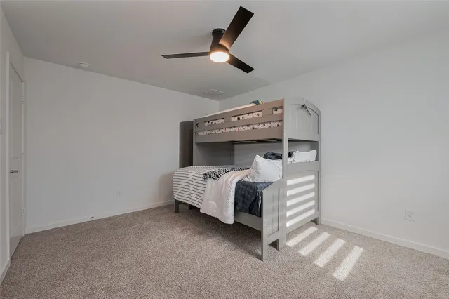 a bed sitting in a room next to a ceiling fan