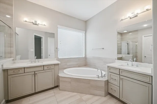 a bathroom with a tub a sink double vanity granite and a mirror