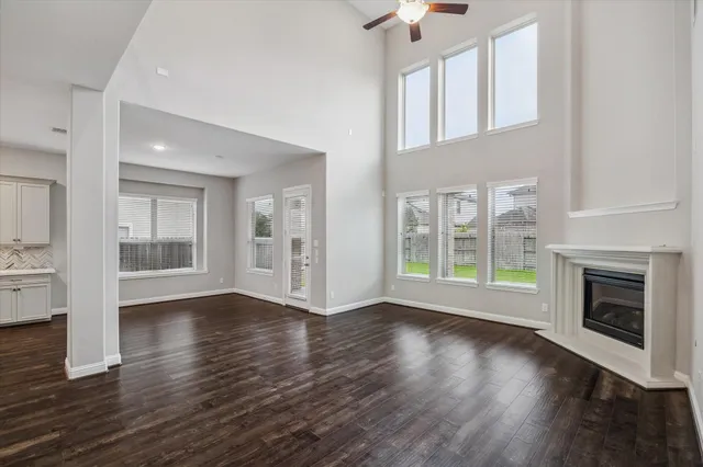a view of an empty room with wooden floor fireplace and a window
