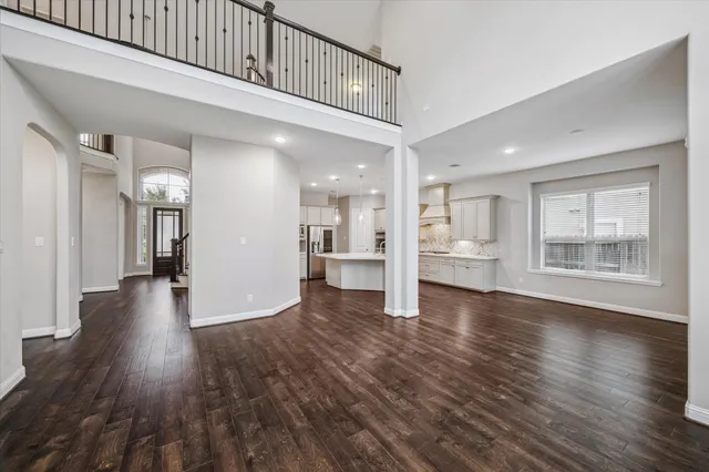 a view of a hallway with wooden floor and a kitchen