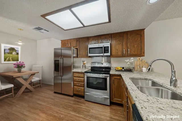 a kitchen with stainless steel appliances granite countertop a sink dishwasher a refrigerator cabinets and a stove top oven