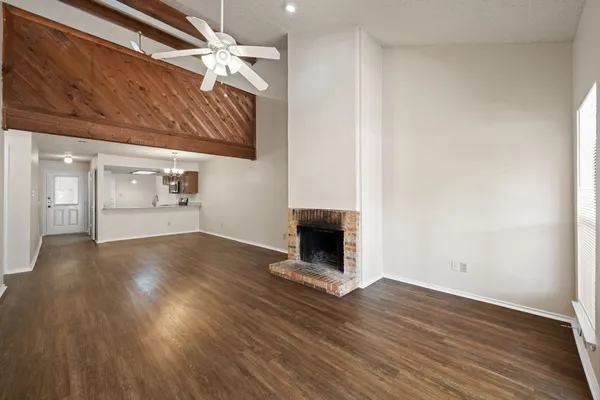 a view of an empty room with wooden floor fireplace and a window