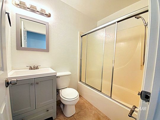 1037 South Ranger Street Ridgecrest, CA 93555 - Photo 13 of 26 a bathroom with a toilet a sink and a mirror