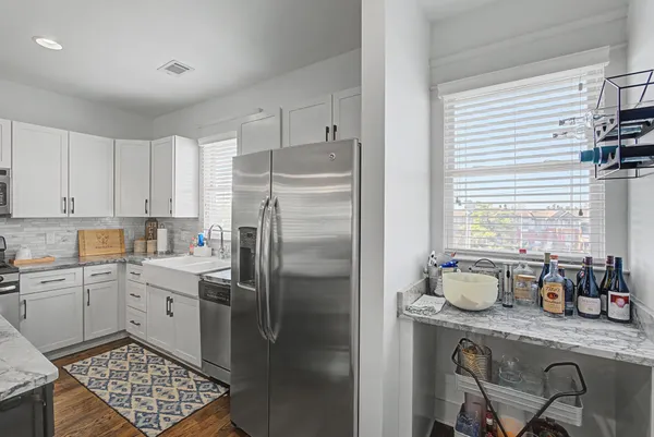 a kitchen with stainless steel appliances granite countertop a refrigerator a sink a stove and white cabinets