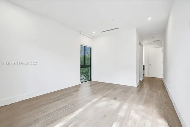 an empty room with wooden floor closet and windows