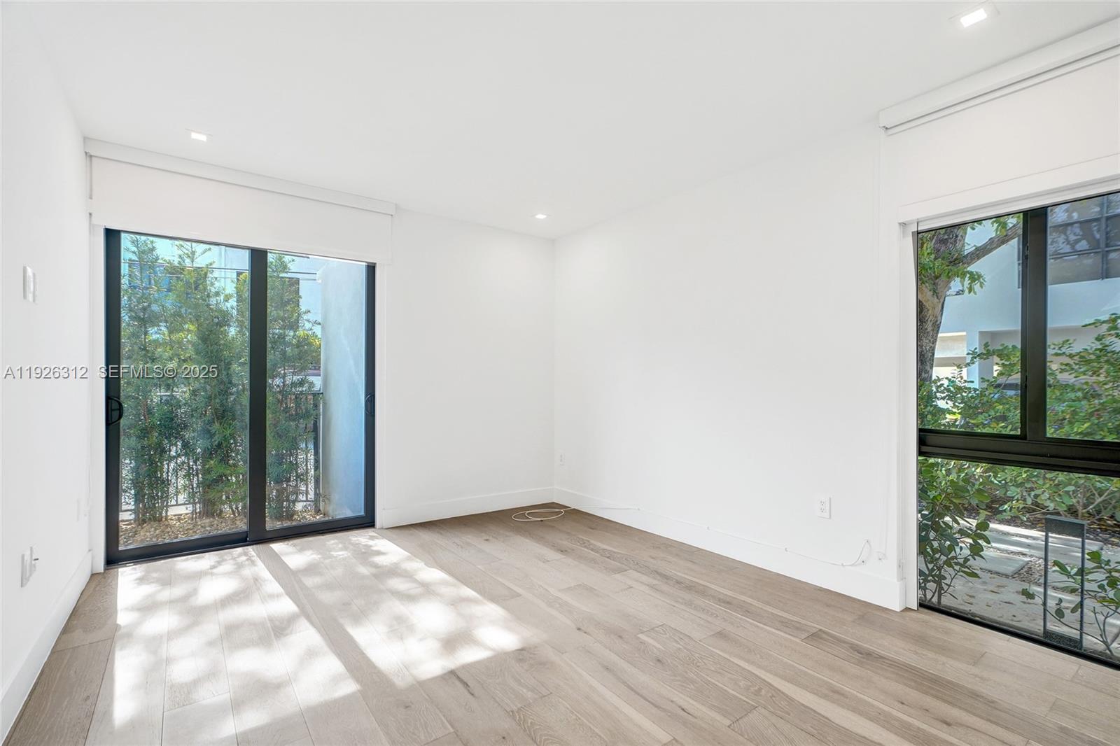 200 Sunrise Drive, Unit 200A Key Biscayne, FL 33149 - Photo 9 of 45 an empty room with wooden floor and windows