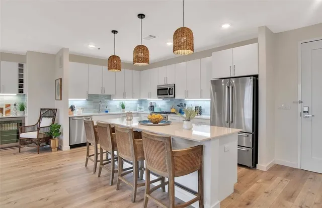 a kitchen with stainless steel appliances granite countertop a dining table chairs refrigerator and microwave