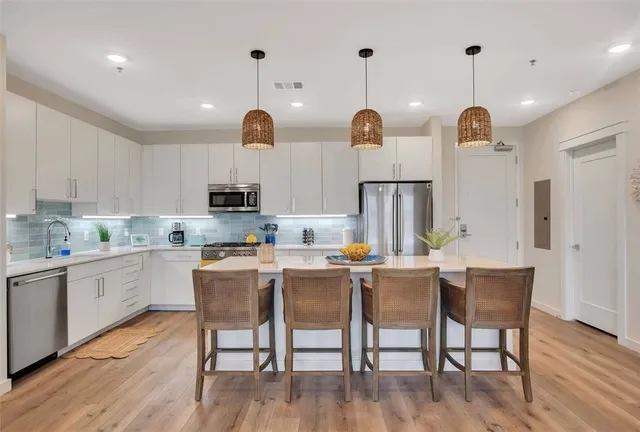 a kitchen with stainless steel appliances granite countertop a dining table chairs sink and stove top oven