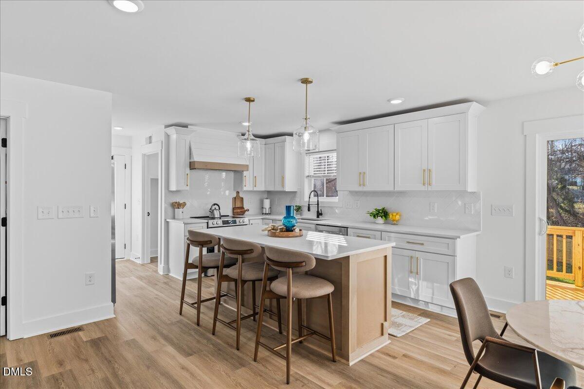 617 North 3rd Street Mebane, NC 27302 - Photo 19 of 50 a kitchen with stainless steel appliances a dining table chairs and wooden floor