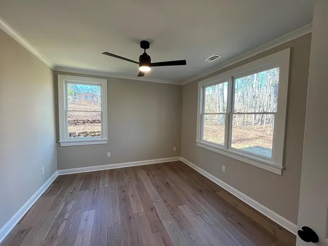 a view of an empty room with wooden floor and a window