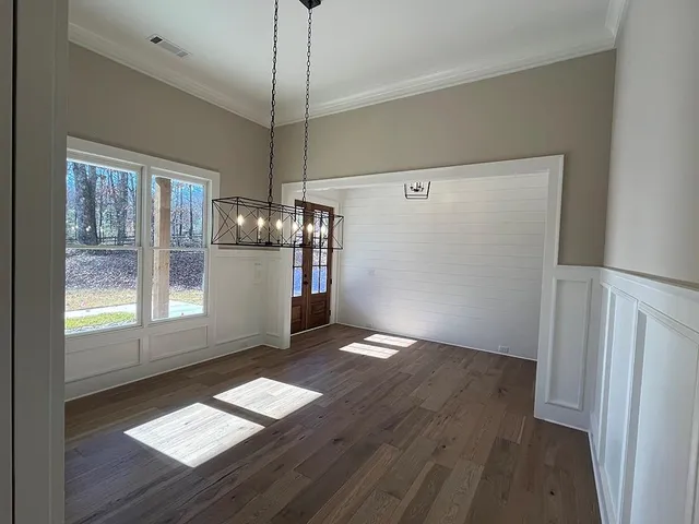 a view of empty room with wooden floor and window