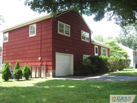 21 Daniel Road Spotswood, NJ 08884 - Photo 11 of 12 a brick house in front of a yard with plants and trees