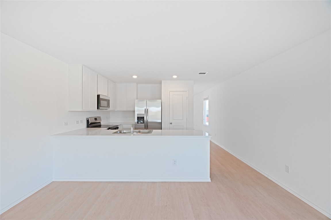241 Kings Row Lane Jarrell, TX 76537 - Photo 8 of 27 a large white kitchen with kitchen island a sink a stove and a refrigerator