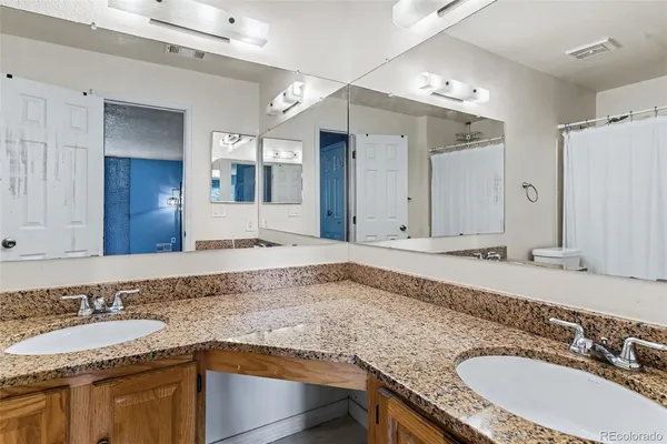 a bathroom with a granite countertop double vanity sink and a mirror