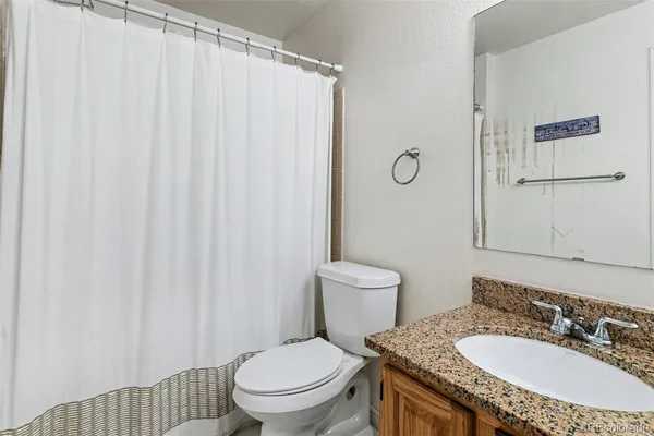 a bathroom with a granite countertop sink a toilet and a mirror
