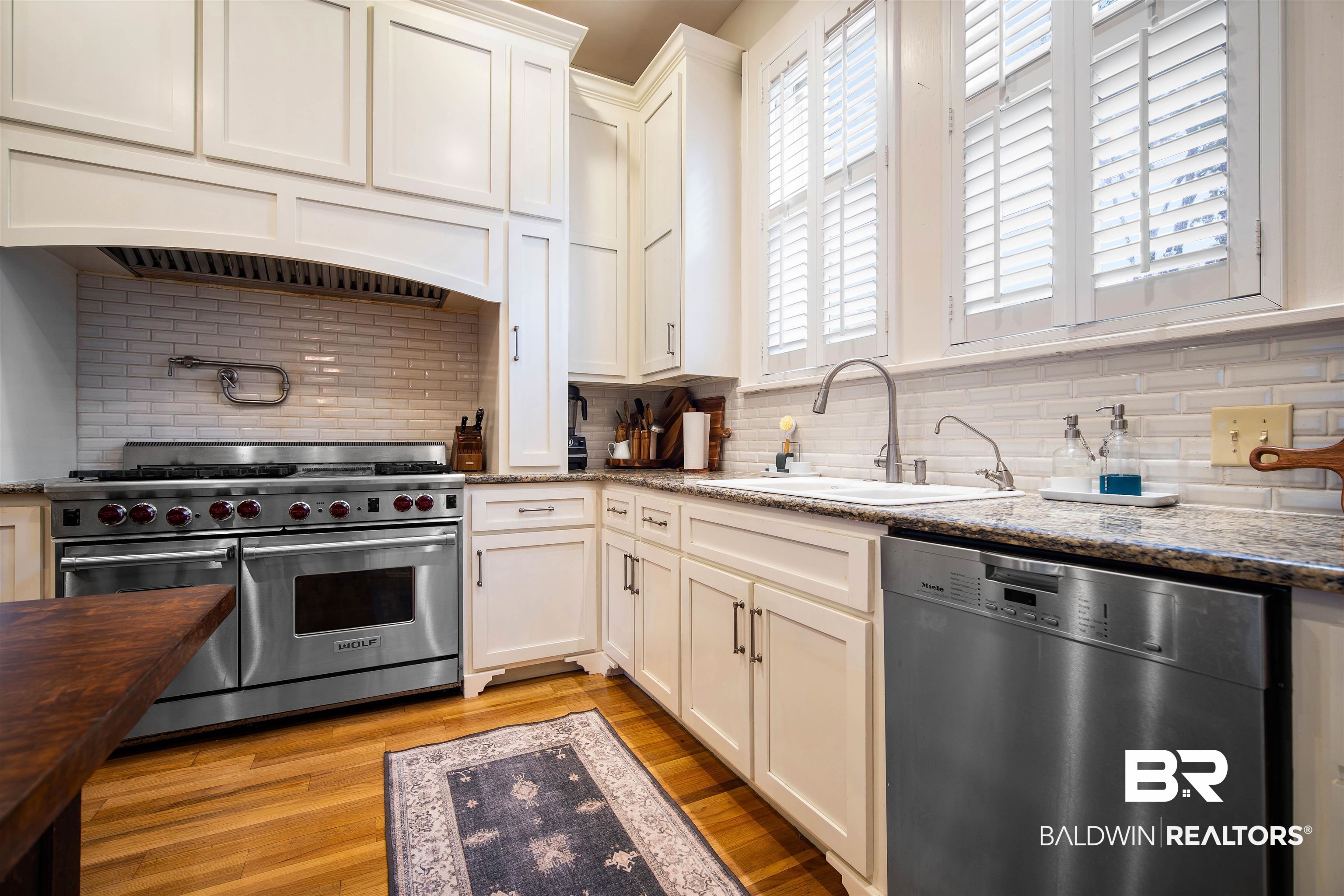 1314 Dauphin Street Mobile, AL 36604 - Photo 25 of 61 Kitchen featuring sink, stainless steel appliances, dark stone countertops, custom range hood, and hardwood flooring