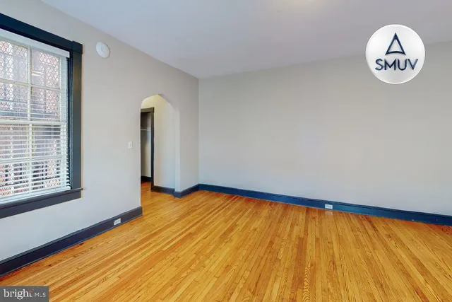 a view of an empty room with window and wooden floor