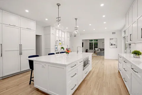 a large white kitchen with a large center island and stainless steel appliances