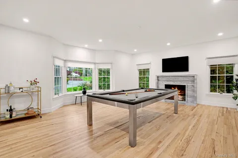 a room with furniture pool table wooden floor and windows