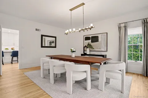 a dining room with wooden floor a chandelier a wooden table and chairs