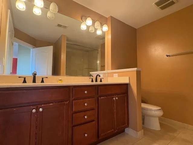a bathroom with a double vanity sink toilet and a mirror
