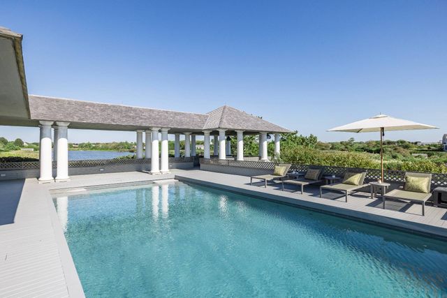 a view of a swimming pool with lawn chairs under an umbrella