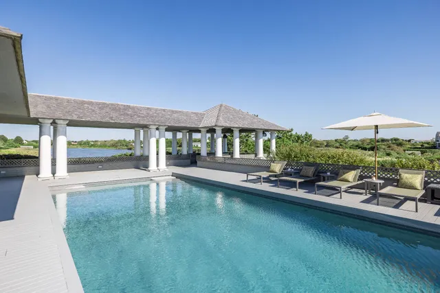 a view of a swimming pool with lawn chairs under an umbrella