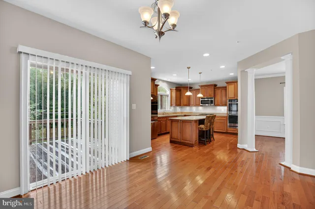 a open kitchen with stainless steel appliances kitchen island granite countertop a refrigerator oven a sink and dishwasher with wooden floor