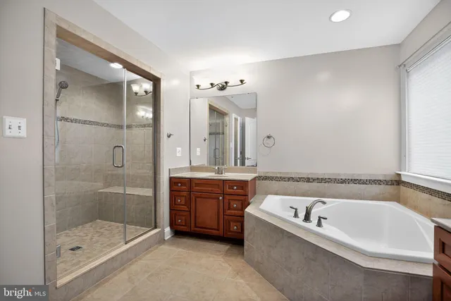 a bathroom with a bathtub a double vanity sink and mirror