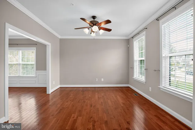a view of empty room with wooden floor and fan