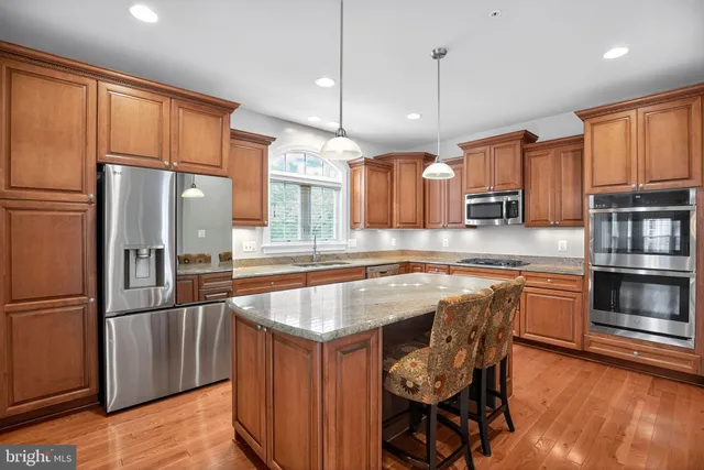 a kitchen with stainless steel appliances granite countertop a refrigerator a sink and a stove