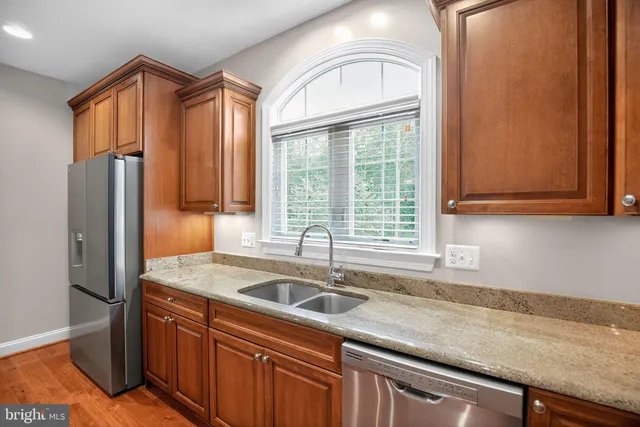 a kitchen with stainless steel appliances granite countertop a sink a refrigerator and window