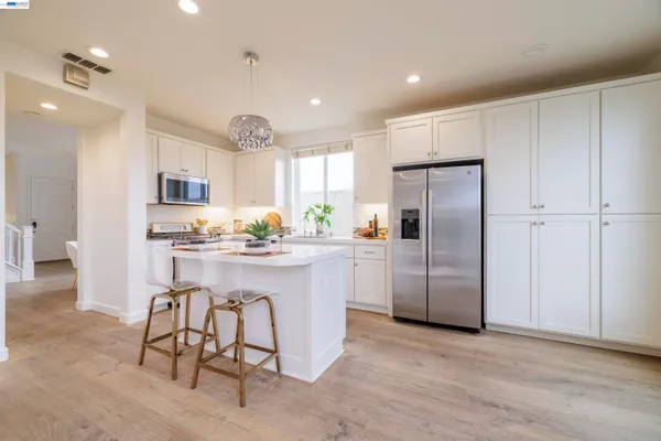 a kitchen with stainless steel appliances granite countertop a refrigerator a sink dishwasher a stove and a refrigerator with wooden floor