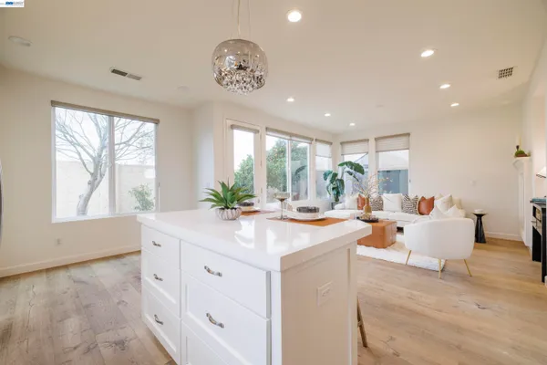 a kitchen with a sink dishwasher stove and white cabinets with wooden floor