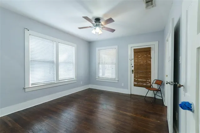 an empty room with wooden floor fan and windows
