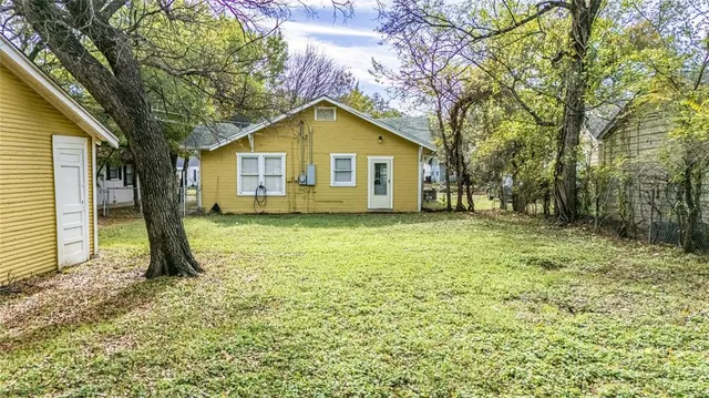 a view of a house with a yard and large tree