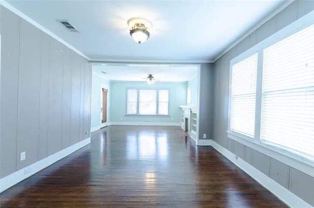 a view of an empty room with a window and wooden floor