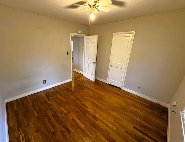 a view of an empty room with wooden floor and staircase