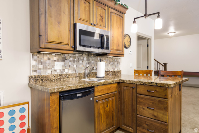 2005 West 450 S Circle St. George, UT 84770 - Photo 24 of 57 Built-in wet bar featuring rich wood cabinetry, a granite-finish countertop, and a mosaic tile backsplash