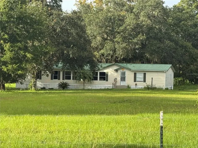a front view of a house with a garden and trees