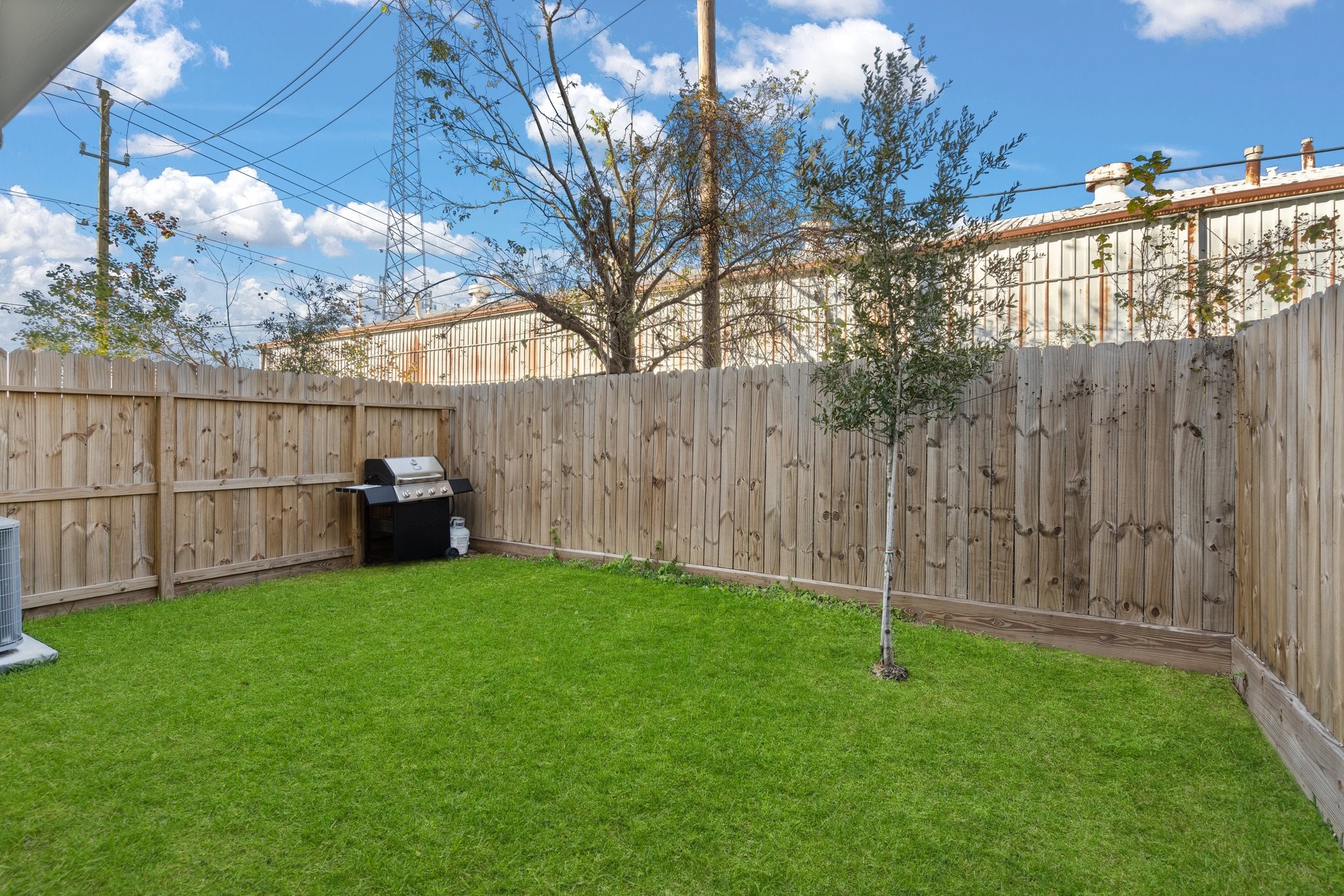 2928 Stevens Street Houston, TX 77026 - Photo 21 of 30 This backyard features a neatly fenced area with a lush green lawn, a young tree, and a barbecue grill, ideal for outdoor gatherings or relaxation.
