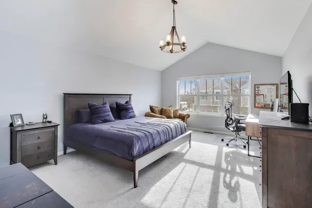 a spacious bedroom with a bed a chandelier and large window
