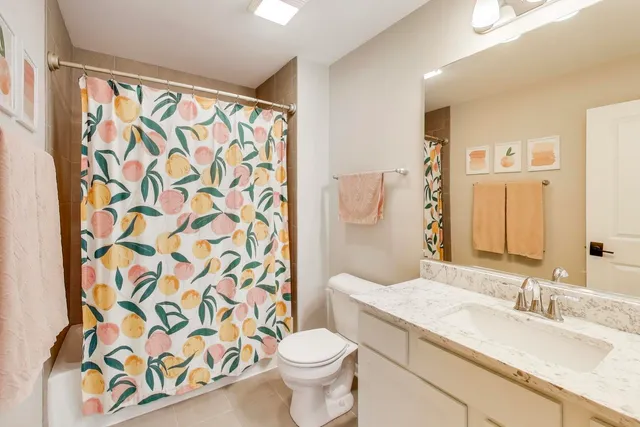 a bathroom with a granite countertop sink a toilet and a shower curtain
