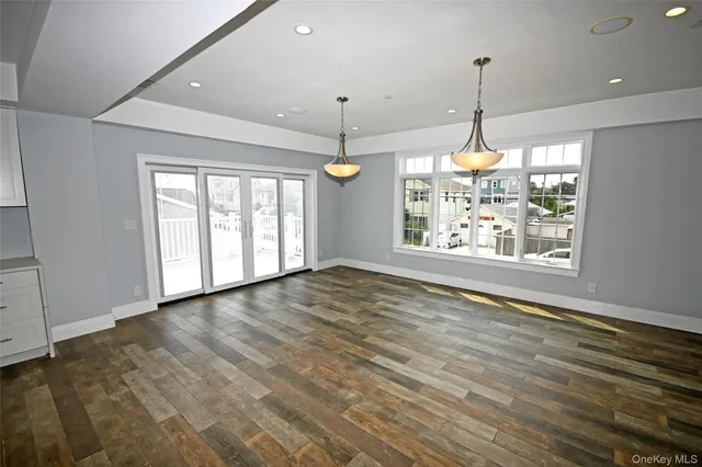 a view of an empty room with window and chandelier