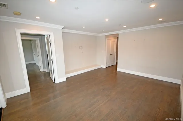 an empty room with wooden floor and windows with curtains