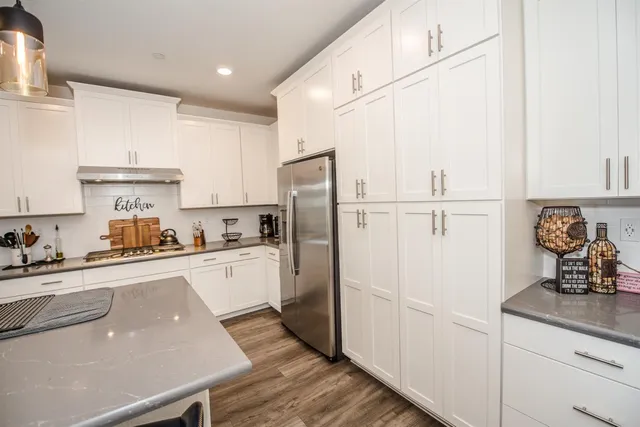 a kitchen with stainless steel appliances granite countertop a sink a stove and white cabinets