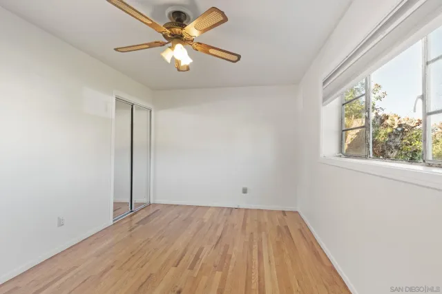 an empty room with a window and a ceiling fan
