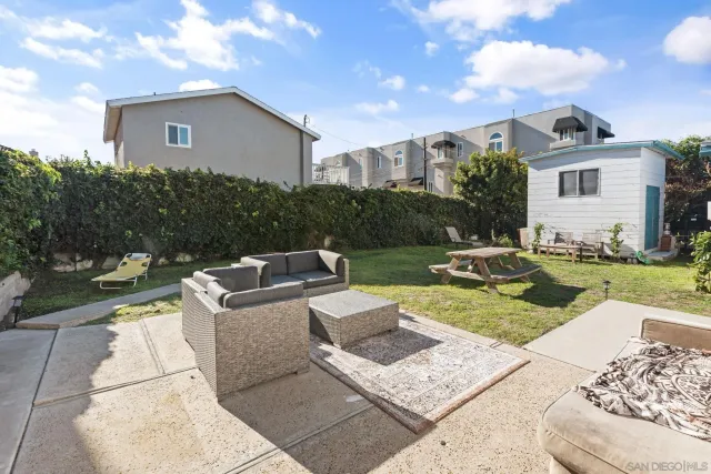 a view of a backyard with table and chairs potted plants and large tree
