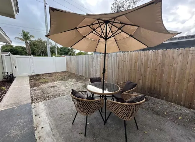a view of wooden table and chairs under an umbrella